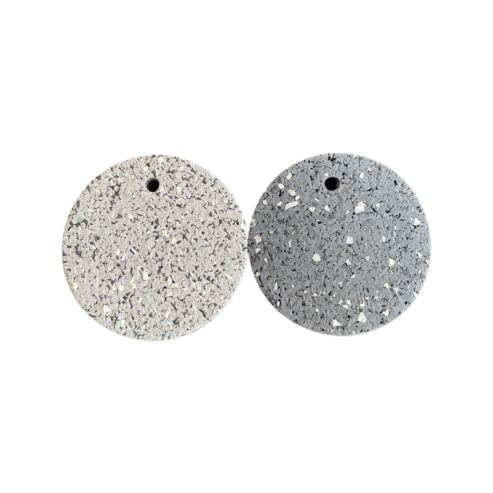 Two round terrazzo samples—light beige &amp; gray—with holes, perfect for 8mm Kodiak Rubber Flooring by Athletic Textiles inspo.