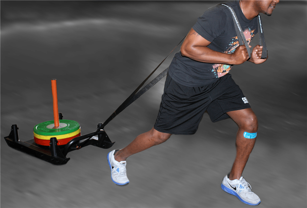 A person trains for acceleration by pulling the Troy VTX Push/Pull Sled &amp; Strap from Troy Barbell on a grey surface.